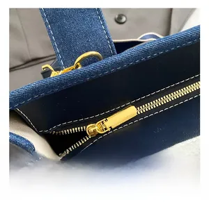 Close-up of deep blue denim texture with white contrast stitching and gold metal hardware