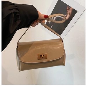 Detail of light brown leather crossbody bag featuring a gold twist lock and a square flap