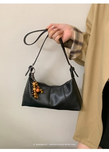 Détail du sac croissant vintage en cuir noir avec perles en bois et anneau métallique