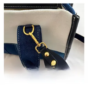 Detail of golden metal hook on contrast denim and canvas tote bag with stitching