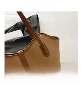 Close-up of brown textured leather tote bag with elegant golden clasp and stitching