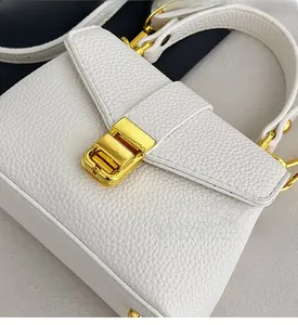 Detail of white lychee leather texture and golden metal square buckle on small handbag
