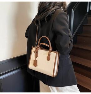 Detail of a small tote bag in cream and brown PU leather with detachable strap on stairs