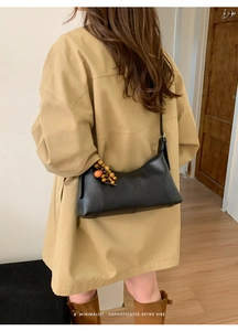 Détail du sac à bandoulière rétro noir avec pendentif unique en perles de bois orange