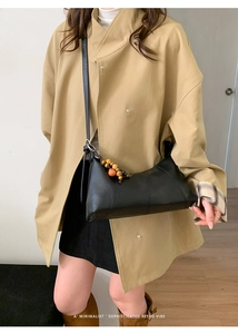 Détail du sac dumpling en cuir noir avec perles décoratives en bois et fine bandoulière