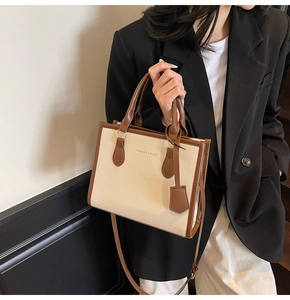 Close-up of a vintage-style patchwork tote bag with gold lettering and brown handles