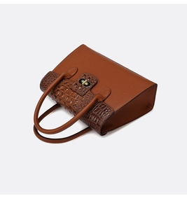 Détail du sac à main en cuir marron avec motifs crocodile et fermoir doré rotatif