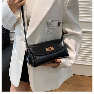 Detail of glossy black patent leather shoulder bag with golden metallic twist lock