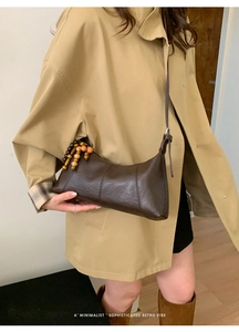 Détail du sac demi-lune en cuir marron foncé avec perles en bois et longue bandoulière