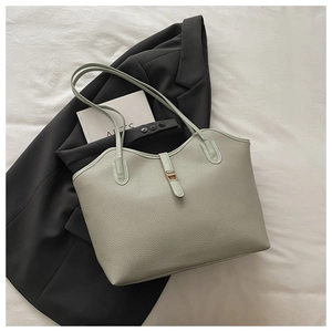 Detail of sage green pebbled leather tote bag featuring a gold rectangular metal clasp