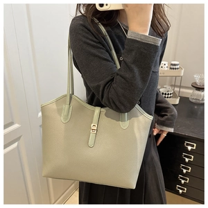 Detail of pistachio green pebble leather tote bag with elegant gold metal clasp closure