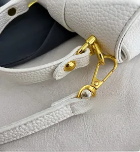 Close-up of golden hardware lobster clasp and white lychee leather strap detail
