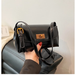 Detail of glossy black leather handbag with elegant gold rectangular rotating clasp hardware