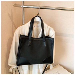 Detail of minimalist black canvas tote bag with leather piping trim and large capacity