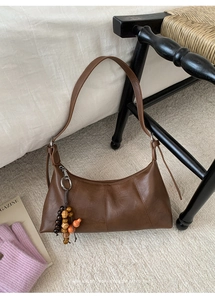 Détail du sac plissé marron rétro avec accessoire de charme en perles de bois vintage