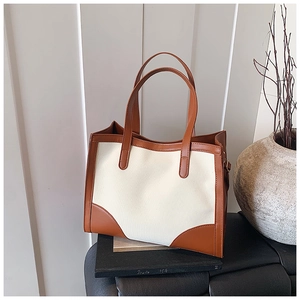 Detail of minimalist tote bag showing contrast stitching and brown leather trim texture