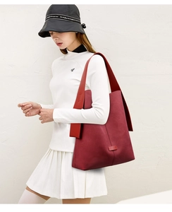 Detail view of large burgundy suede shoulder bag with wide strap on model