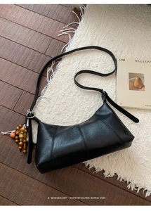 Détail du sac vintage noir en cuir texturé avec breloque en perles de bois