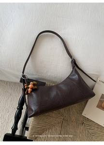 Détail d'un sac rétro marron café avec triple surpiqûre et pendentif en bois