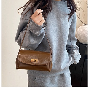 Detail of vintage brown textured leather bag with gold buckle on a gray sweater