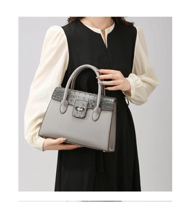 Detail of grey lychee leather handbag with crocodile pattern flap and metal twist lock