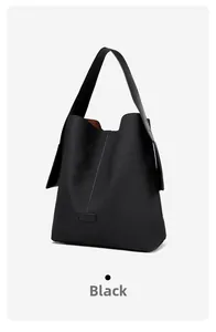Detail of the black minimalist tote bag showing vertical stitching and matte leather texture