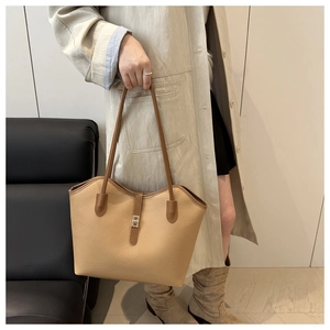 Close-up of litchi texture leather tote bag with gold metal lock and long straps