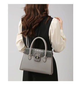 Detail of grey pebbled leather handbag with crocodile pattern flap and gold twist lock