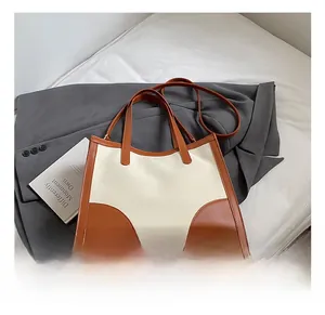 Close-up of contrast stitching on canvas tote bag with brown leather handles and strap