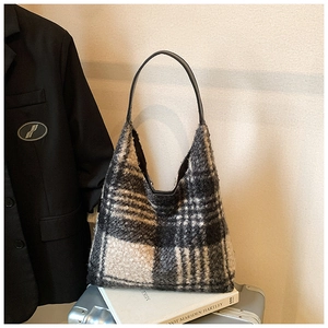Detail of checkered faux fur tote bag with leather straps on a silver suitcase