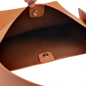 Close-up of magnetic buckle and handmade stitching on brown leather shoulder bag