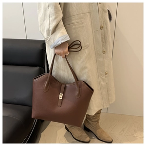 Close-up of a brown leather tote bag with gold metal clasp and textured pebble grain finish