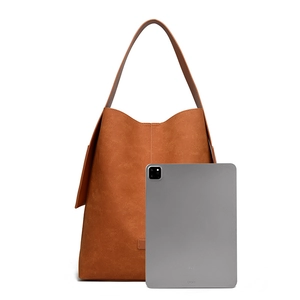 Detail view of large caramel suede tote bag compared with a tablet for scale