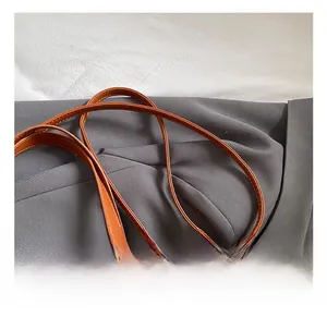 Detail of adjustable brown leather shoulder strap with neat stitching on a blazer