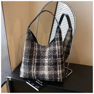 Detail of hobo bag with black and white plaid wool texture and sleek leather strap