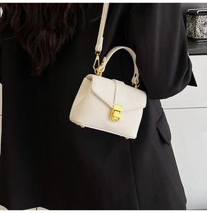 Detail of white leather mini bag with gold metal clasp and adjustable shoulder strap