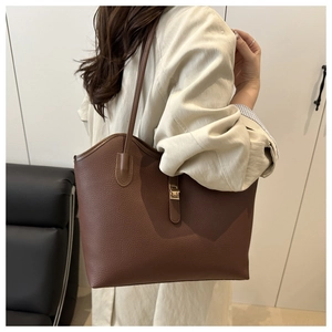 Litchi texture leather tote bag with gold metal buckle shown in a lifestyle setting