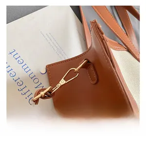 Detail of the golden metal hook on the canvas and brown leather patchwork tote bag