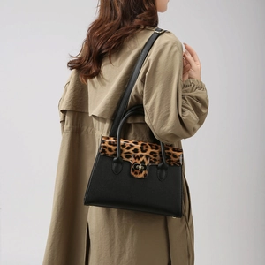 Vue détaillée du sac à main léopard et cuir noir porté avec un trench-coat classique
