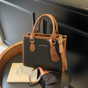 Chic two-tone black and brown textured faux leather tote bag with top handle and shoulder strap