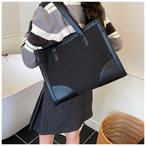 Detail of minimalist black large-capacity canvas tote bag with leather piping on shoulder
