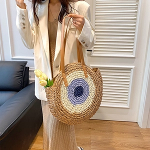 Bohemian round woven straw shoulder bag with blue concentric patterns and leather straps