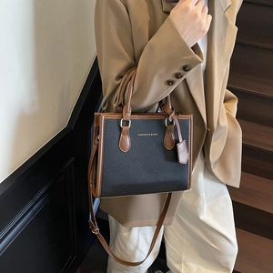Classic black and brown tote bag with gold lettering shown in a stylish indoor setting