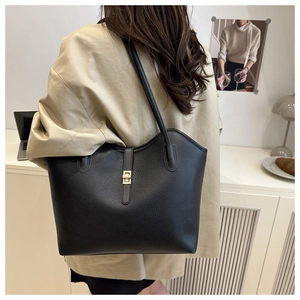 Close-up of black lychee grain leather tote bag featuring a golden twist lock closure