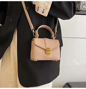 Close-up of nude lychee pattern leather handbag with gold metal clasp on a model