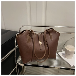 Macro view of dark brown lychee texture leather tote with golden rectangular twist lock