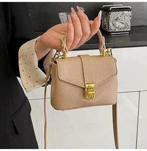Detail of lychee textured leather bag with gold twist lock and elegant shoulder strap