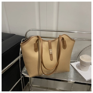 Detail of beige textured leather tote with brown handles and golden swivel lock