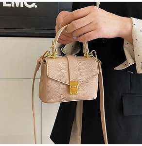 Close-up of pink lychee grain leather handbag featuring golden lock and crossbody strap