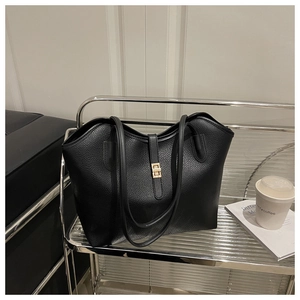 Close-up of black pebbled leather tote bag featuring a polished gold rectangular metal buckle